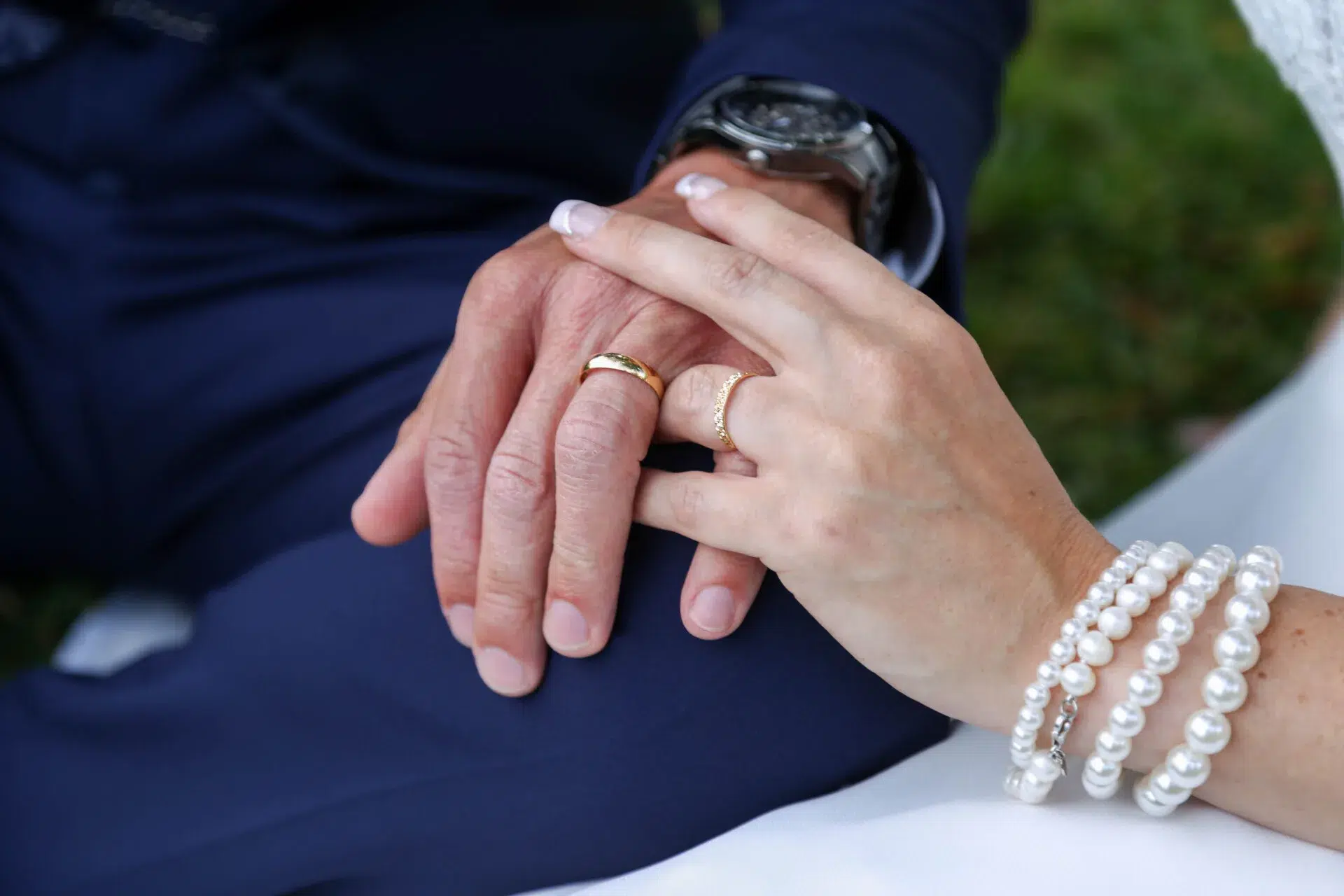 Mains des mariés entrelacées montrant leurs alliances de mariage