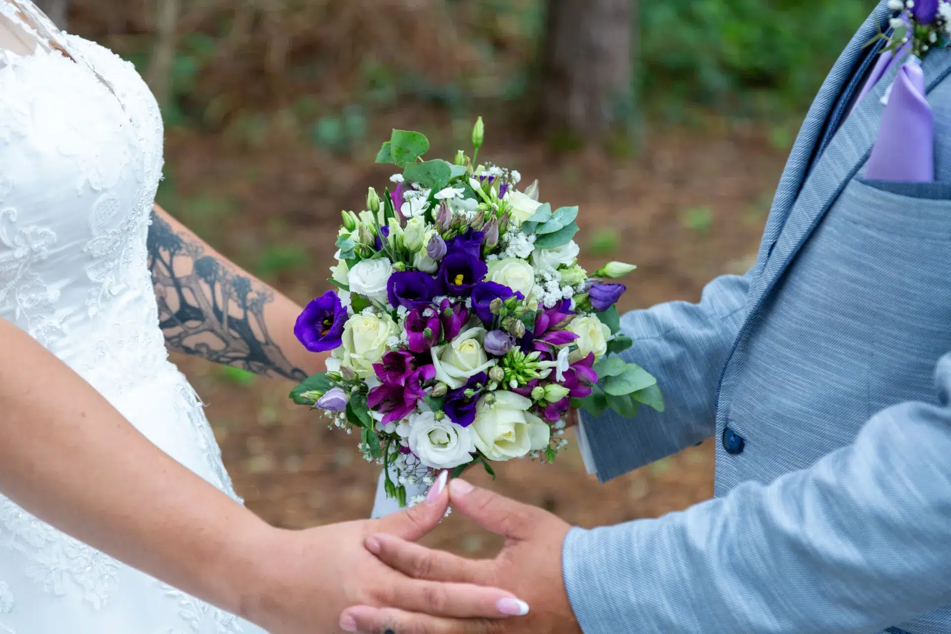 Bridge And Groom Standing While Holding Flower Bouquet